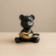 Black bear figurine holding a gold coin on a beige background