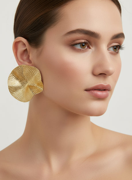 Woman wearing gold earrings on a neutral background