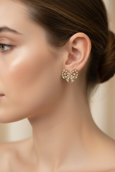 Close-up of a woman wearing a decorative bow-shaped earring with a blurred background