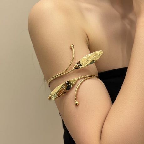 Gold leaf-like arm cuff on a person against a neutral background