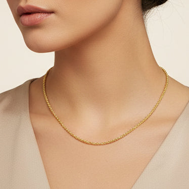 Woman wearing a gold bead necklace on a whtie background