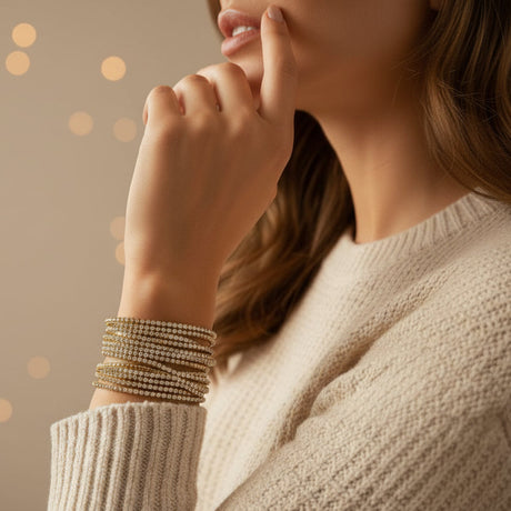 Woman wearing multiple gold bracelets on a blurred background