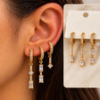 Ear wearing three gold pave huggies with long baguette crystal drops, with the set shown on a card