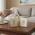 Gold bifold frame opened like a book on a walnut table beside a vase of peonies