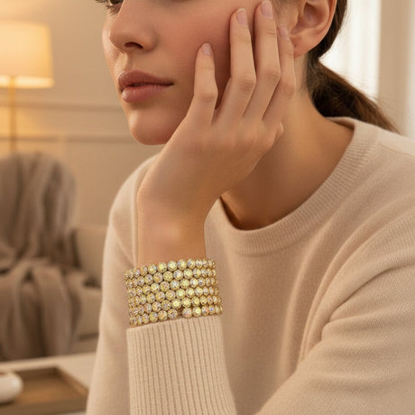 Woman wearing a gold beaded bracelet in a cozy indoor setting