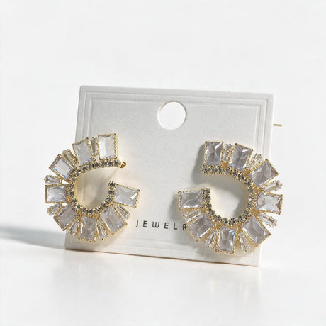 Pair of gold emerald cut crystal crescent earrings on a white display card