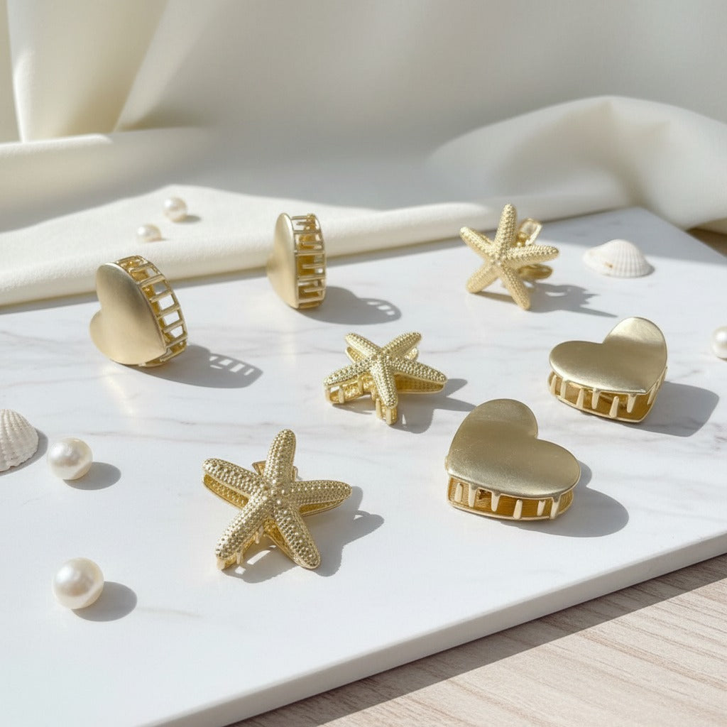 Gold heart, star and starfish claw clips on white marble