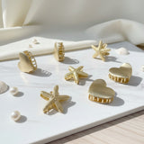 Gold heart, star and starfish claw clips on white marble