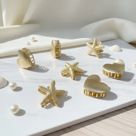 Gold heart, star and starfish claw clips on white marble