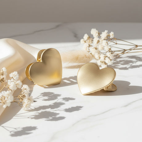 Two brushed gold heart claw clips beside dried babys breath flowers