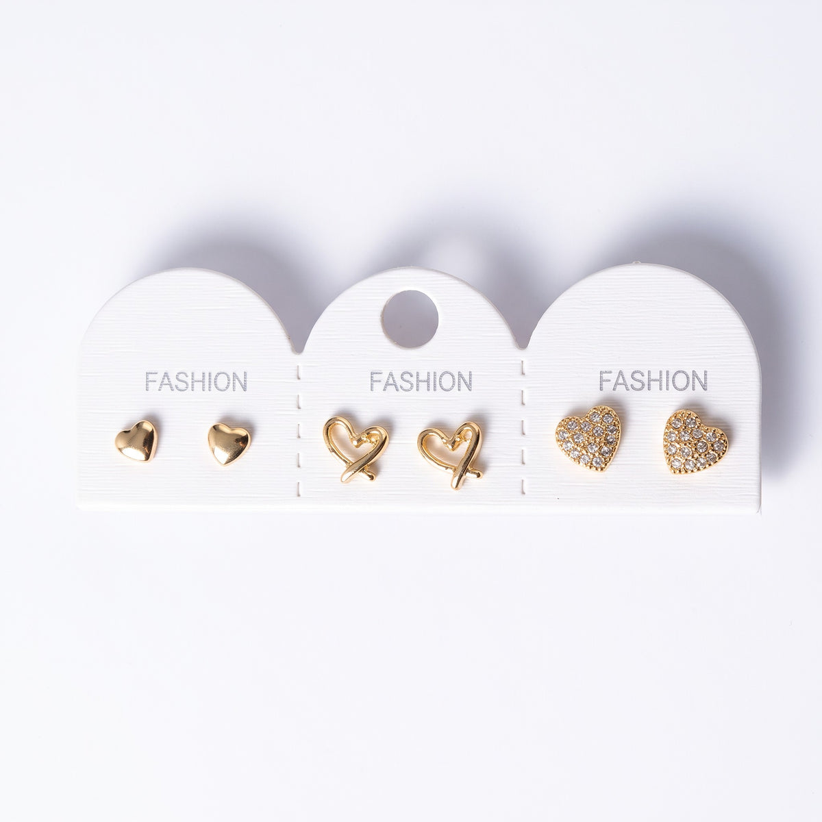 Three pairs of gold heart stud earrings on a card, polished, open and pave set