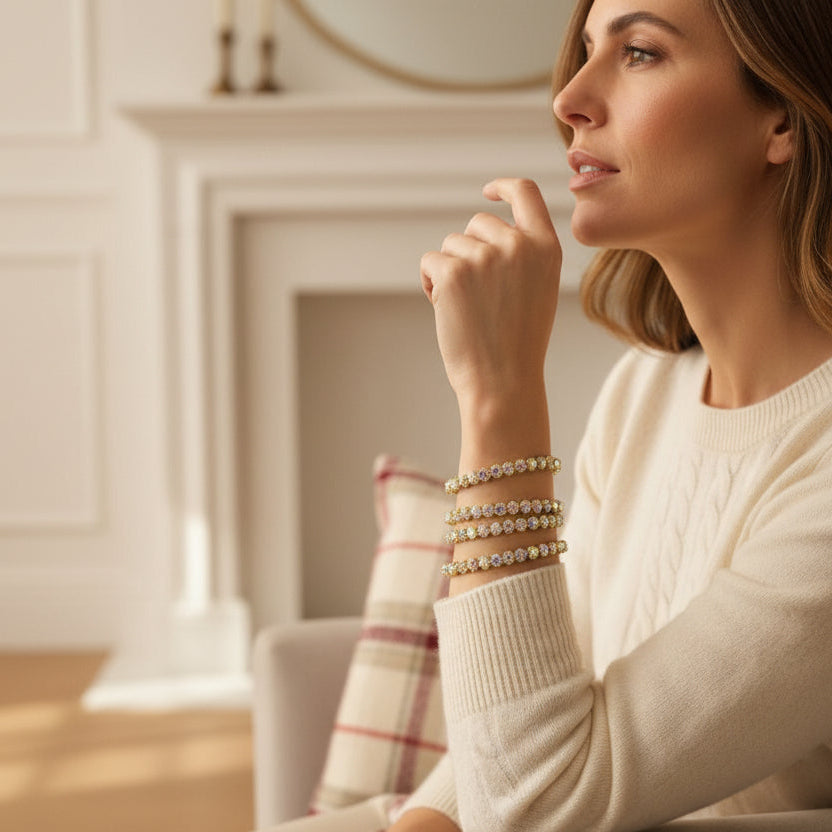 Woman wearing multiple gold bracelets in a cozy indoor setting