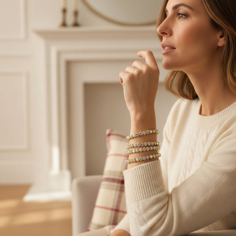 Woman wearing multiple gold bracelets in a cozy indoor setting
