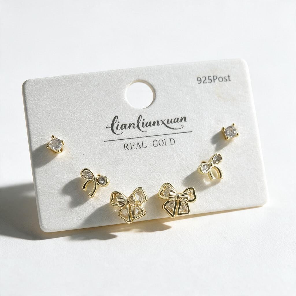 Gold stud set with round crystal studs, small open bows and larger pave edged bows on a white card