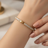 Gold baguette tennis bracelet with clear stones worn by a person