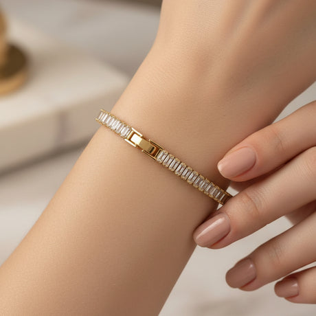 Gold baguette tennis bracelet with clear stones worn by a person