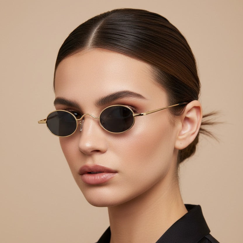 Woman wearing gold-framed sunglasses with a neutral background