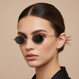 Woman wearing gold-framed sunglasses with a neutral background
