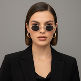 Woman wearing small gold-framed and round retro sunglasses with a plain background