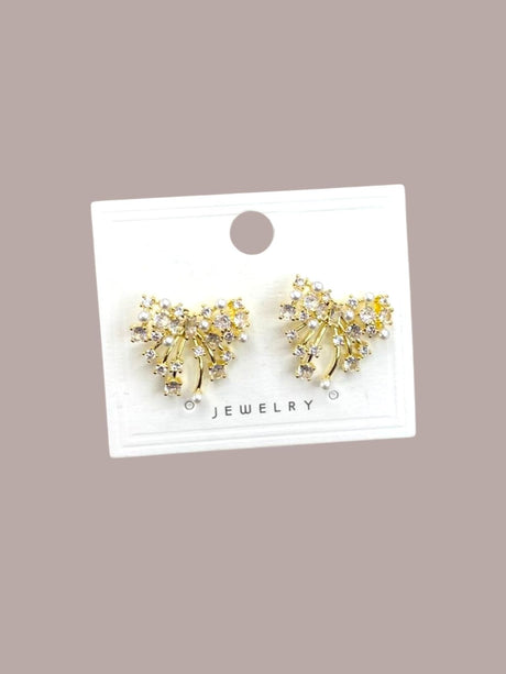 Gold sparkly bow earrings on a jewelry card against a beige background