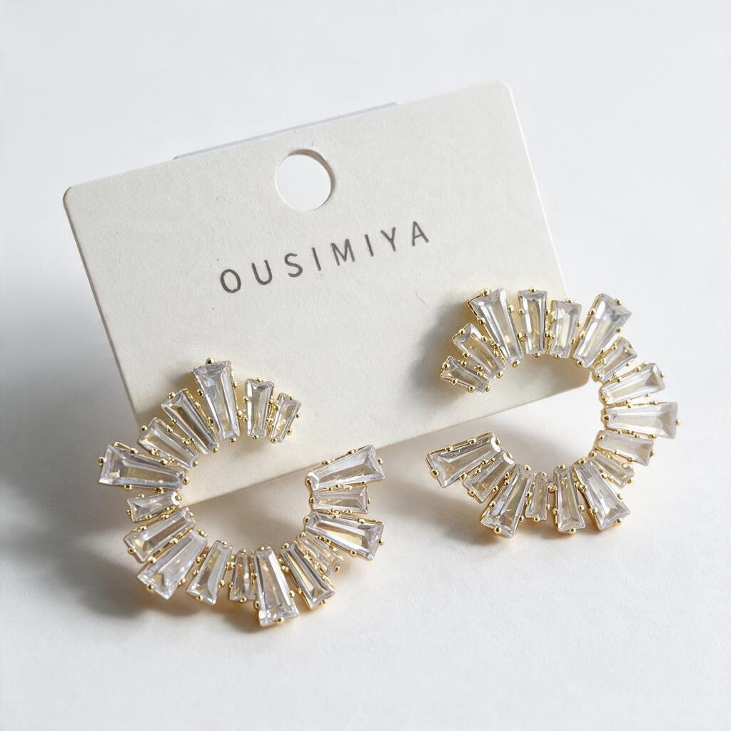 Pair of gold tapered baguette crystal spiral earrings on a white display card