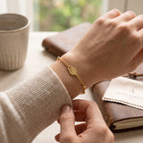 Gold tone tulip charm bracelet on a fine beaded chain worn on a wrist
