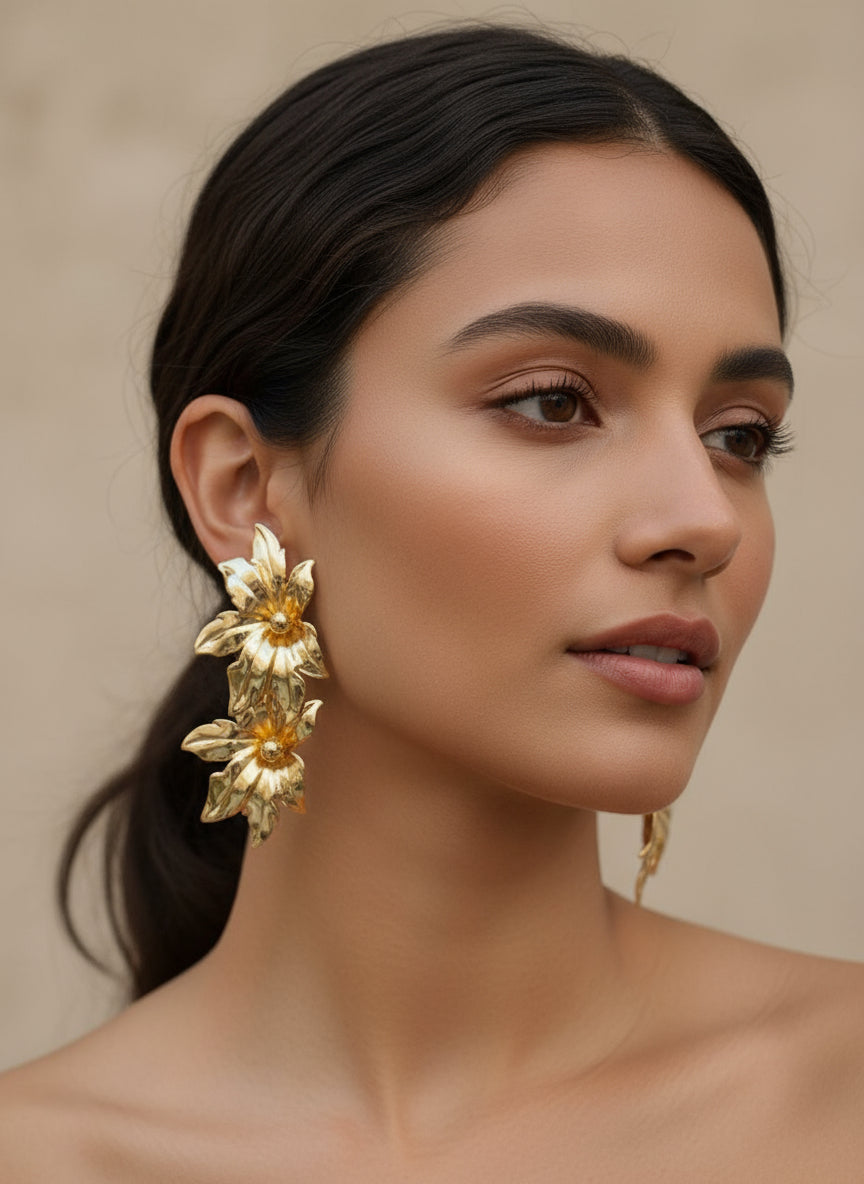Woman wearing gold floral earrings against a beige background