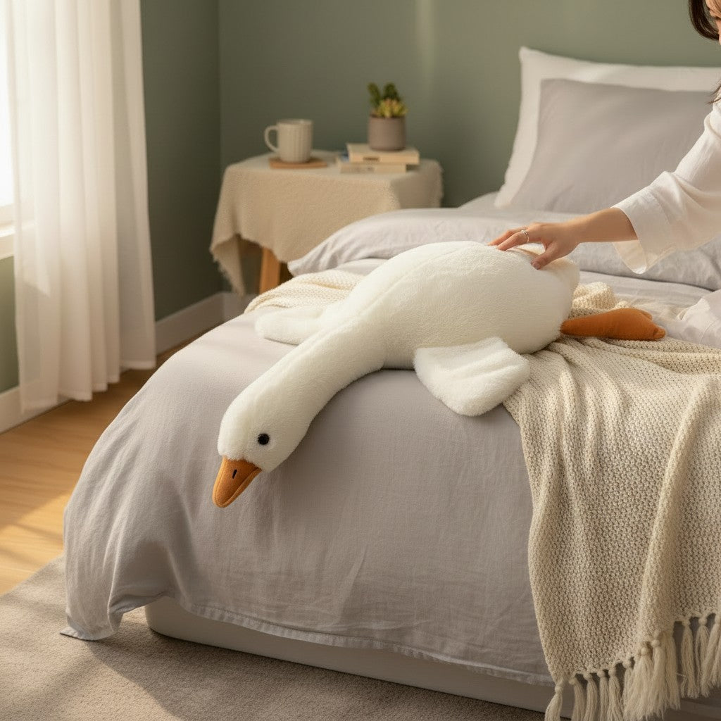 White plush goose resting across a bed in a softly lit bedroom