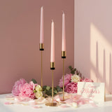 Gold holders with black collars and pink tapers among peonies and trailing ribbons