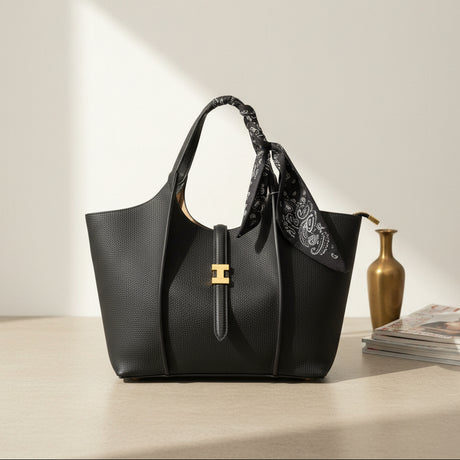 Black graceful handbag with gold clasp styled beside a vase and books