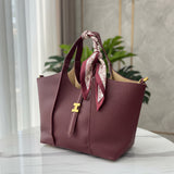 Burgundy handbag with a matching scarf on a white surface with a neutral background
