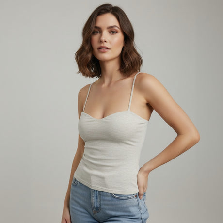 Woman wearing a light gray tank top and blue jeans against a neutral background