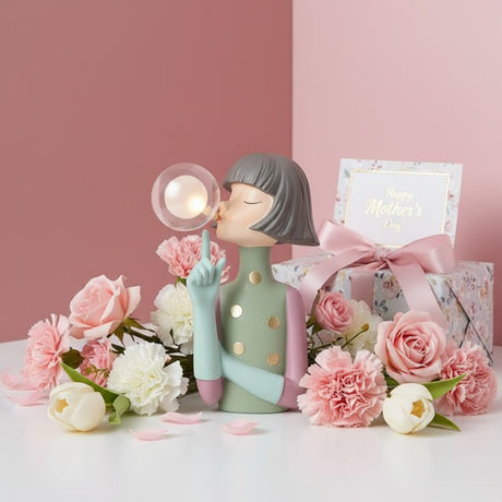 Sage green figure with mint arms and gold spots beside a floral print gift box