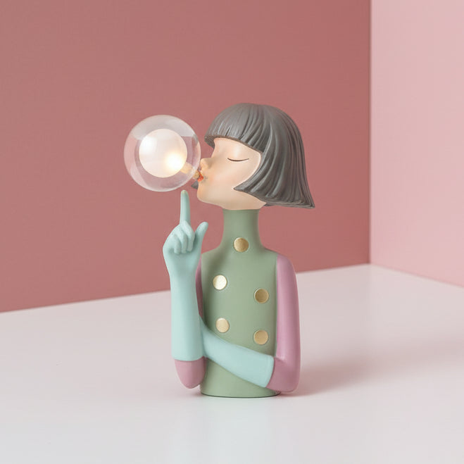 Gold spotted sage dress, pink cuffs and a mint hand pointing up at her lit globe