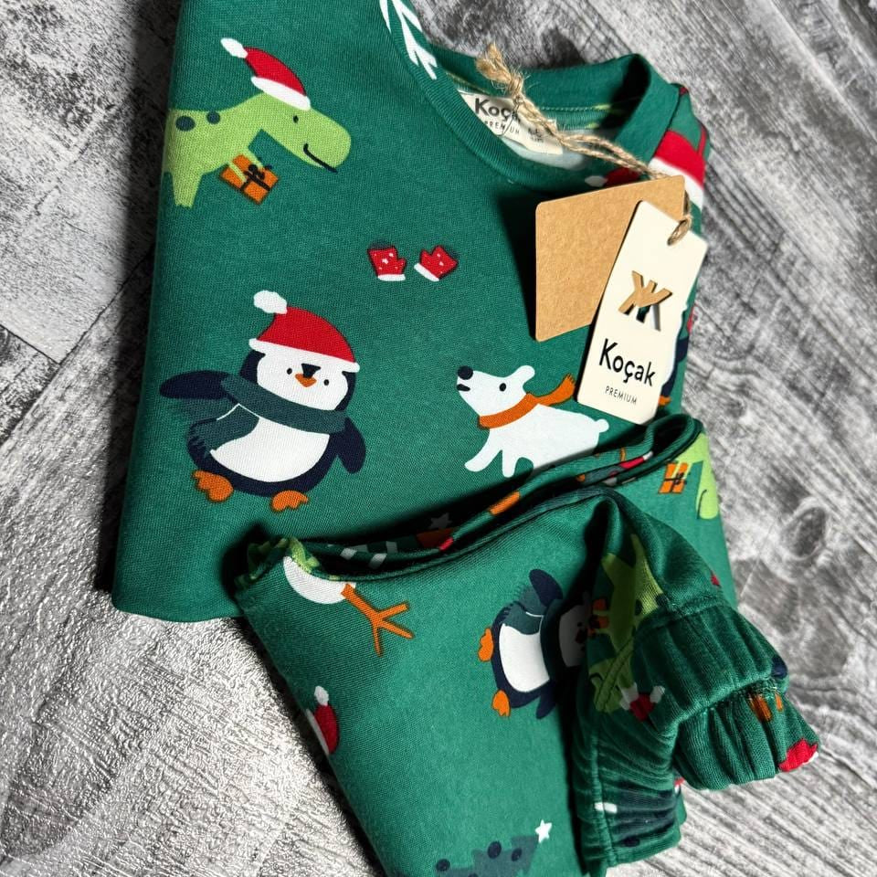 Close up of penguins in Santa hats and polar bears on green pajama fabric