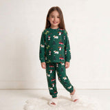 Smiling girl in a green Christmas pajama set with penguins and polar bears