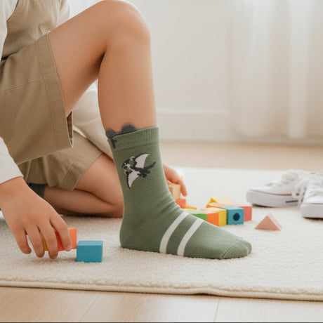 Sage green dinosaur socks with double stripe cuff shown on a wooden floor
