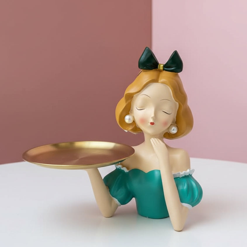 Dark green bow and teal green ruffled dress above an empty gold pedestal tray