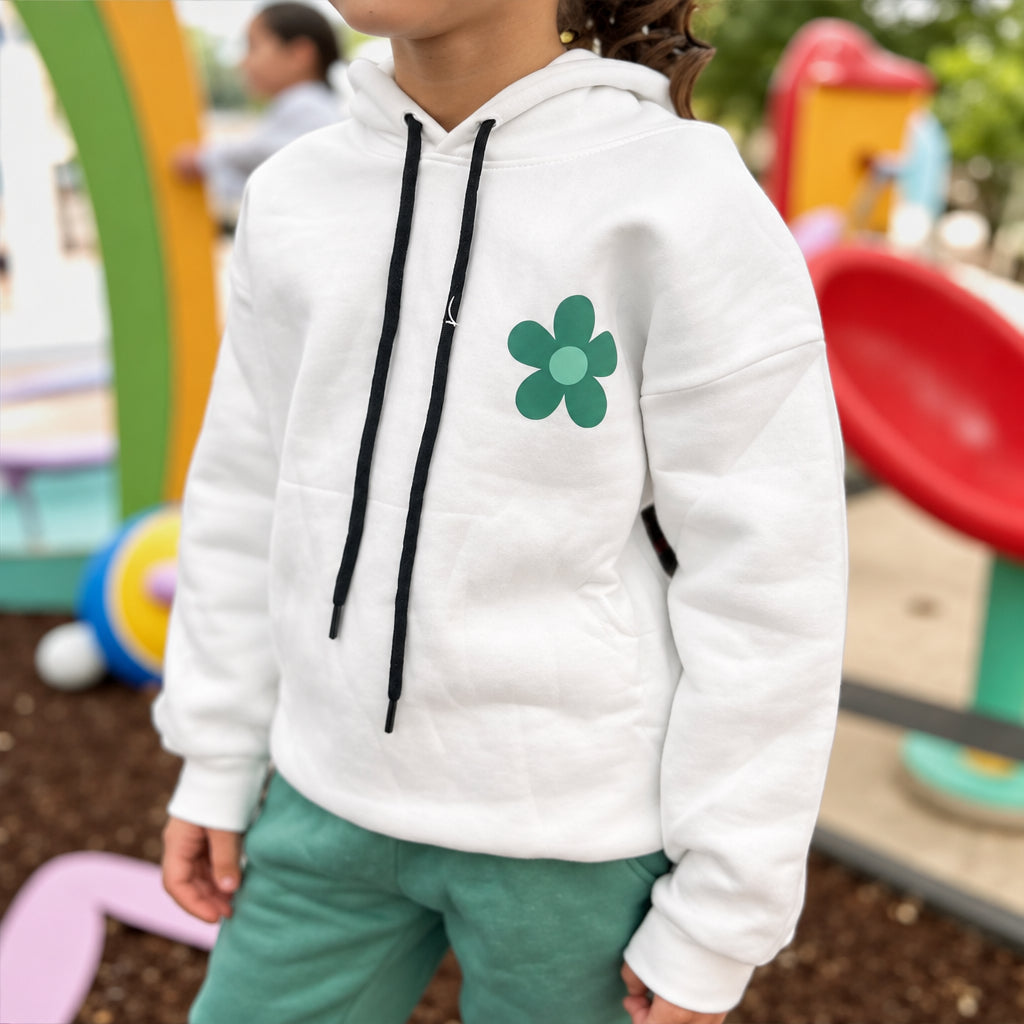 Close view of the green daisy motif on the white hoodie with green jogger bottoms