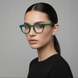 Woman wearing green glasses against a grey background