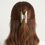 Pale green and pink floral claw clip seen from behind in auburn hair