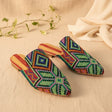 Green handmade slippers on a beige fabric background