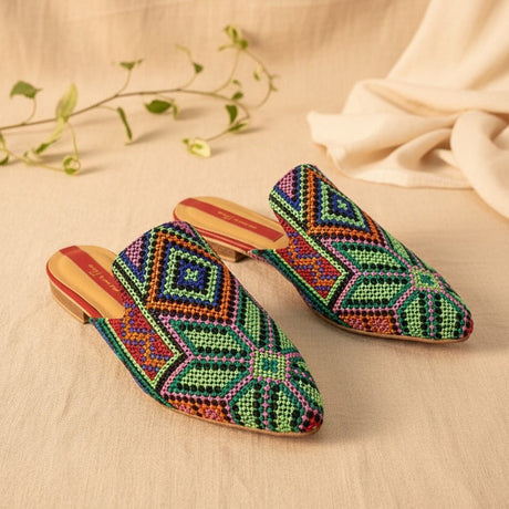 Green handmade slippers on a beige fabric background