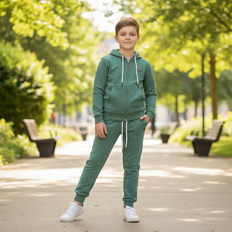 Boy wearing a green zip up hooded jacket and matching joggers on a tree lined path