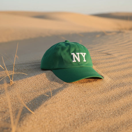 Green embroidered cotton cap on sand dunes with dry grass at sunset