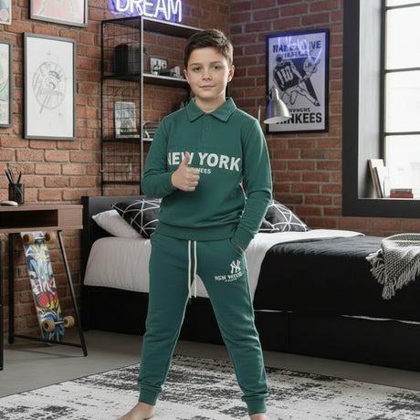 Boy in a dark green New York collared sweatshirt and matching joggers standing in a bedroom