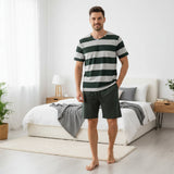 Green striped pyjama set worn standing in a bright bedroom beside a bed