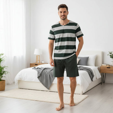 Green striped pyjama set worn standing in a bright bedroom beside a bed
