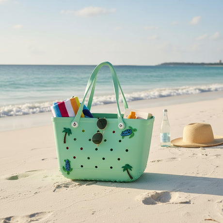 Light green beach bag with decorative elements on a sandy beach with ocean view