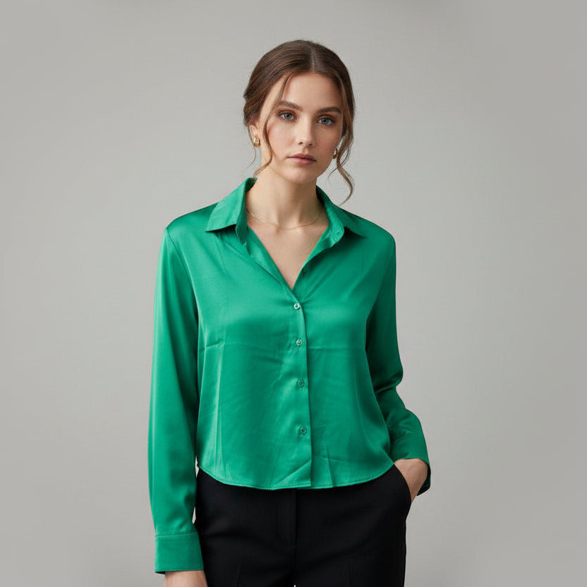 Woman wearing a green sik blouse against a gray background